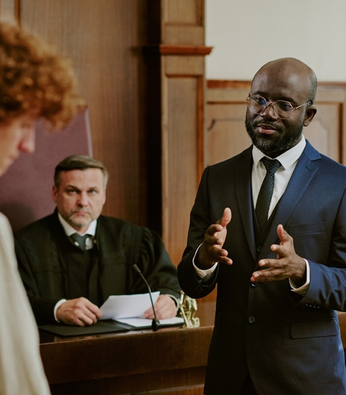 Lawyer presenting a case in courtroom with judge observing.
