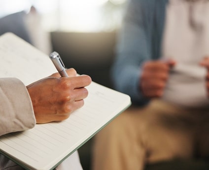 Close-up of psychiatrist taking notes during a therapy session.