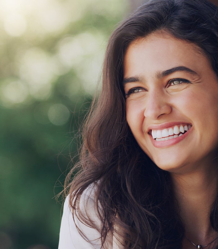Smiling young woman outdoors, symbolizing happiness and improved mental health.