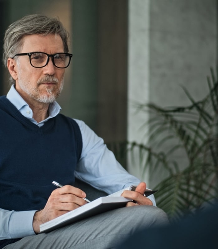 Senior psychiatrist taking notes during a patient session.